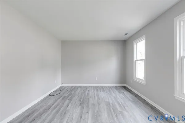 an empty room with wooden floor and windows