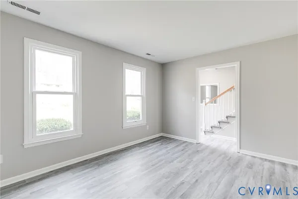 an empty room with wooden floor and windows