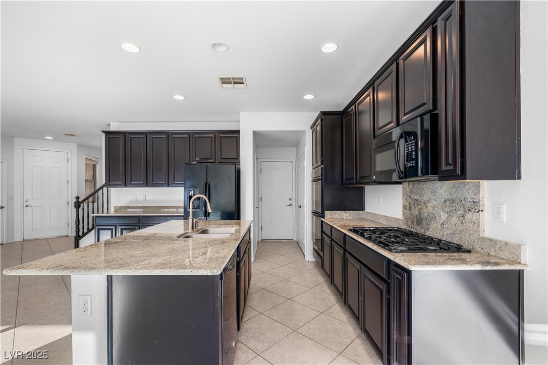10059 Lady Apple Drive Las Vegas, NV 89148 - Photo 7 of 31 Kitchen with light tile patterned floors, light stone countertops, recessed lighting, black appliances, and a center island with sink