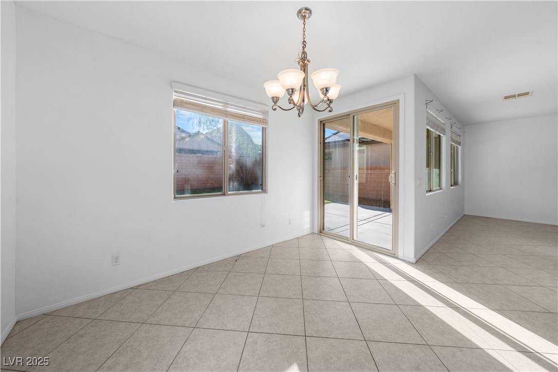 10059 Lady Apple Drive Las Vegas, NV 89148 - Photo 8 of 31 Empty room with a chandelier and light tile patterned flooring
