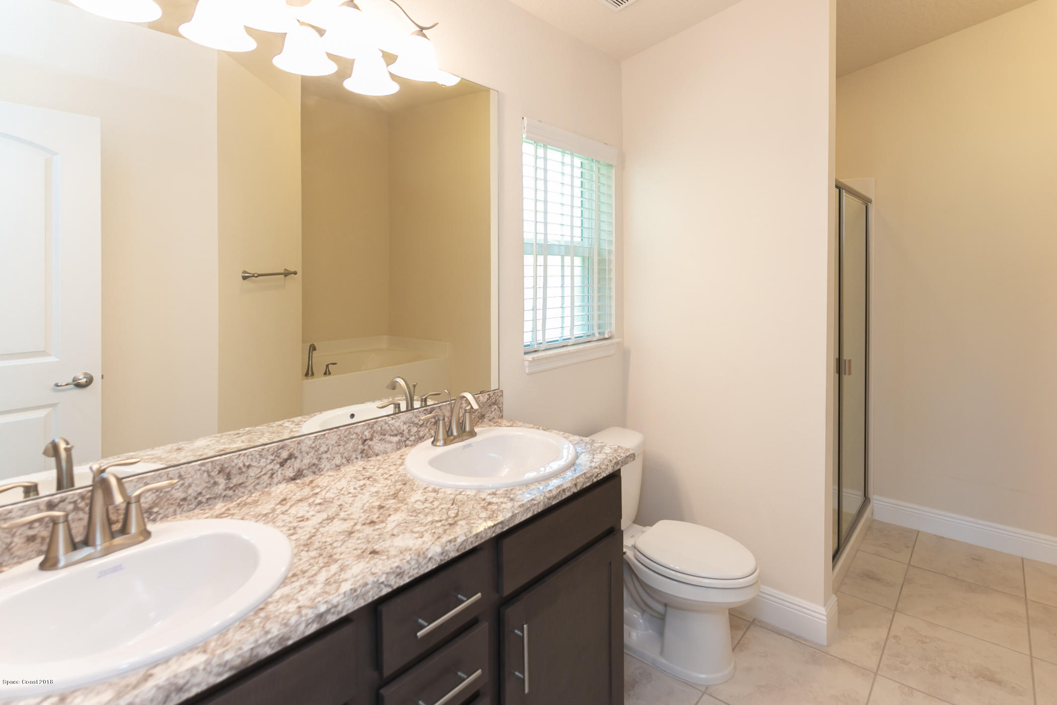 1168 Hathaway Road Southwest Palm Bay, FL 32908 - Photo 7 of 9 a bathroom with a granite countertop sink a toilet and a mirror