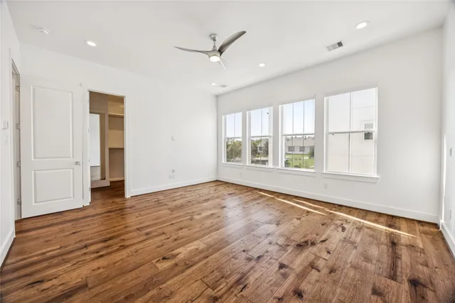 an empty room with wooden floor and windows