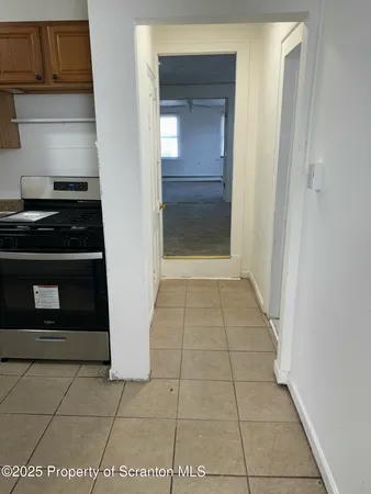 a view of an empty room and a kitchen