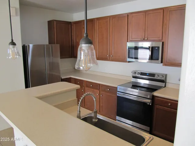 a kitchen with stainless steel appliances a refrigerator a stove a sink and cabinets