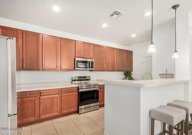 a kitchen with stainless steel appliances granite countertop a stove a sink dishwasher and a refrigerator with wooden cabinets