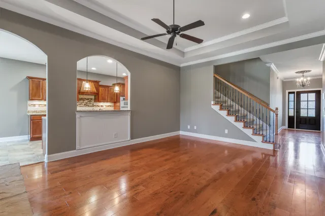 an empty room with wooden floor fan and windows