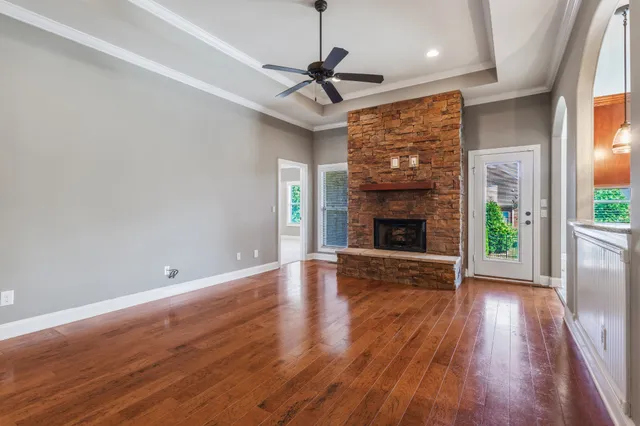 a view of an empty room with wooden floor fireplace and a window