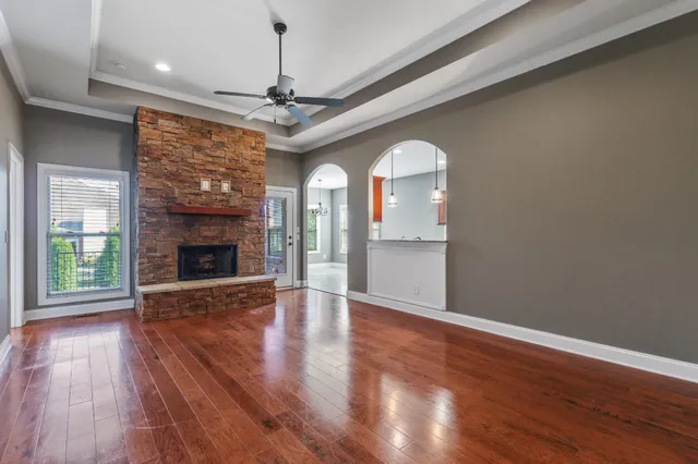 a view of a livingroom with wooden floor a fireplace window and a kitchen space