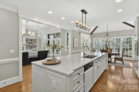 a large kitchen with granite countertop a large center island a stove and a wooden floors