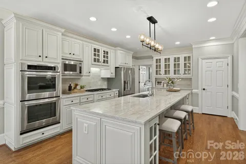 a kitchen with stainless steel appliances kitchen island granite countertop a sink stove oven and refrigerator