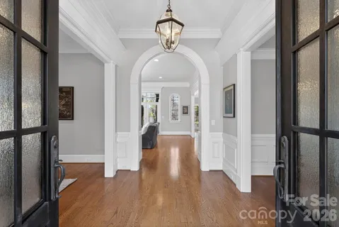 a view of a hallway with wooden floor and a chandelier