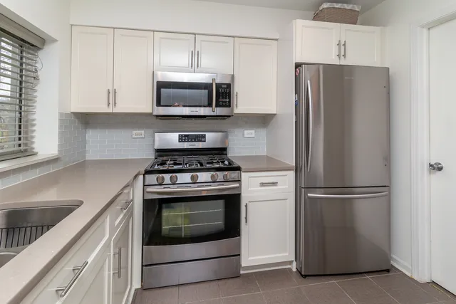a kitchen with stainless steel appliances white cabinets white stove a microwave and a refrigerator