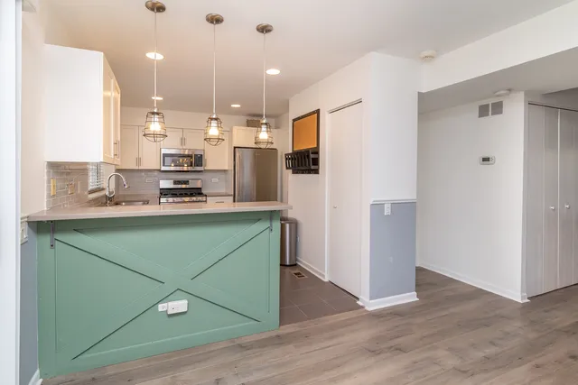 a kitchen with kitchen island a refrigerator and a sink