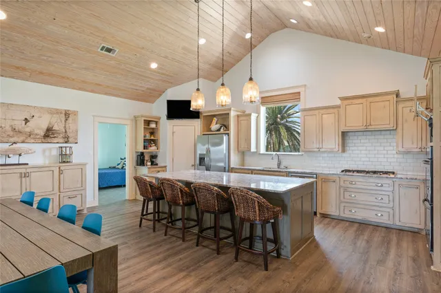 a kitchen with granite countertop a stove a sink a dining table and chairs with wooden floor