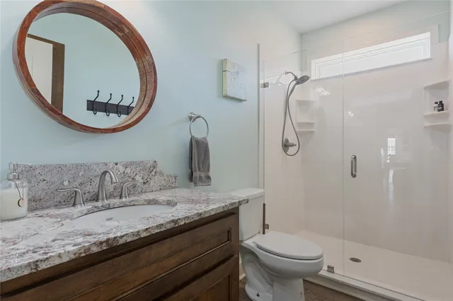 a bathroom with a granite countertop toilet a sink and a mirror