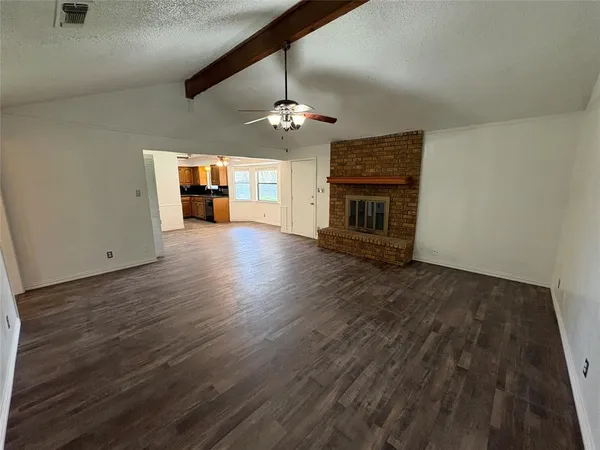 an empty room with wooden floor ceiling fan and window