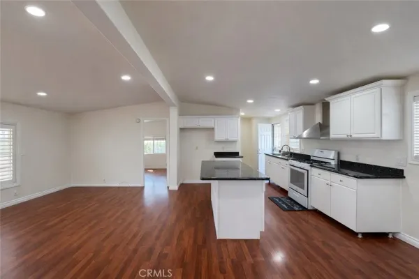 a large kitchen with stainless steel appliances granite countertop a large counter top a stove and a wooden floors