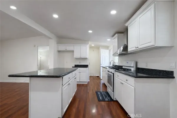 a kitchen with granite countertop a sink a stove and cabinets