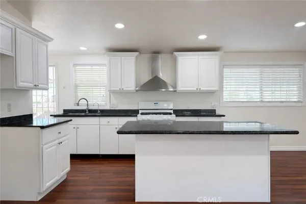 a kitchen with granite countertop white cabinets and a sink