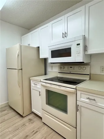a kitchen with stainless steel appliances white cabinets white stove a microwave and a refrigerator
