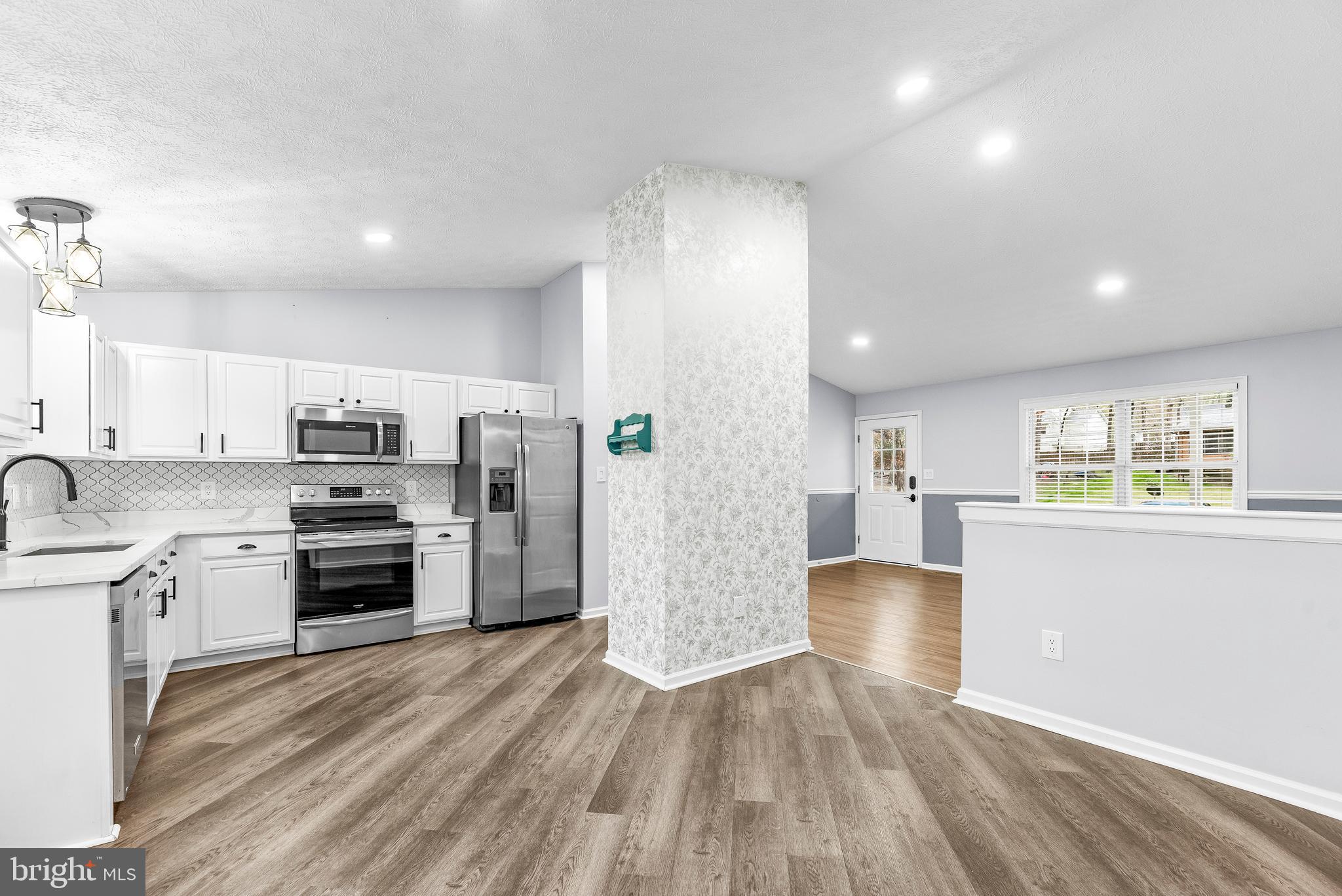 307 Red Cloud Road Lusby, MD 20657 - Photo 7 of 35 a kitchen with stainless steel appliances granite countertop a refrigerator a stove and a sink with wooden floors