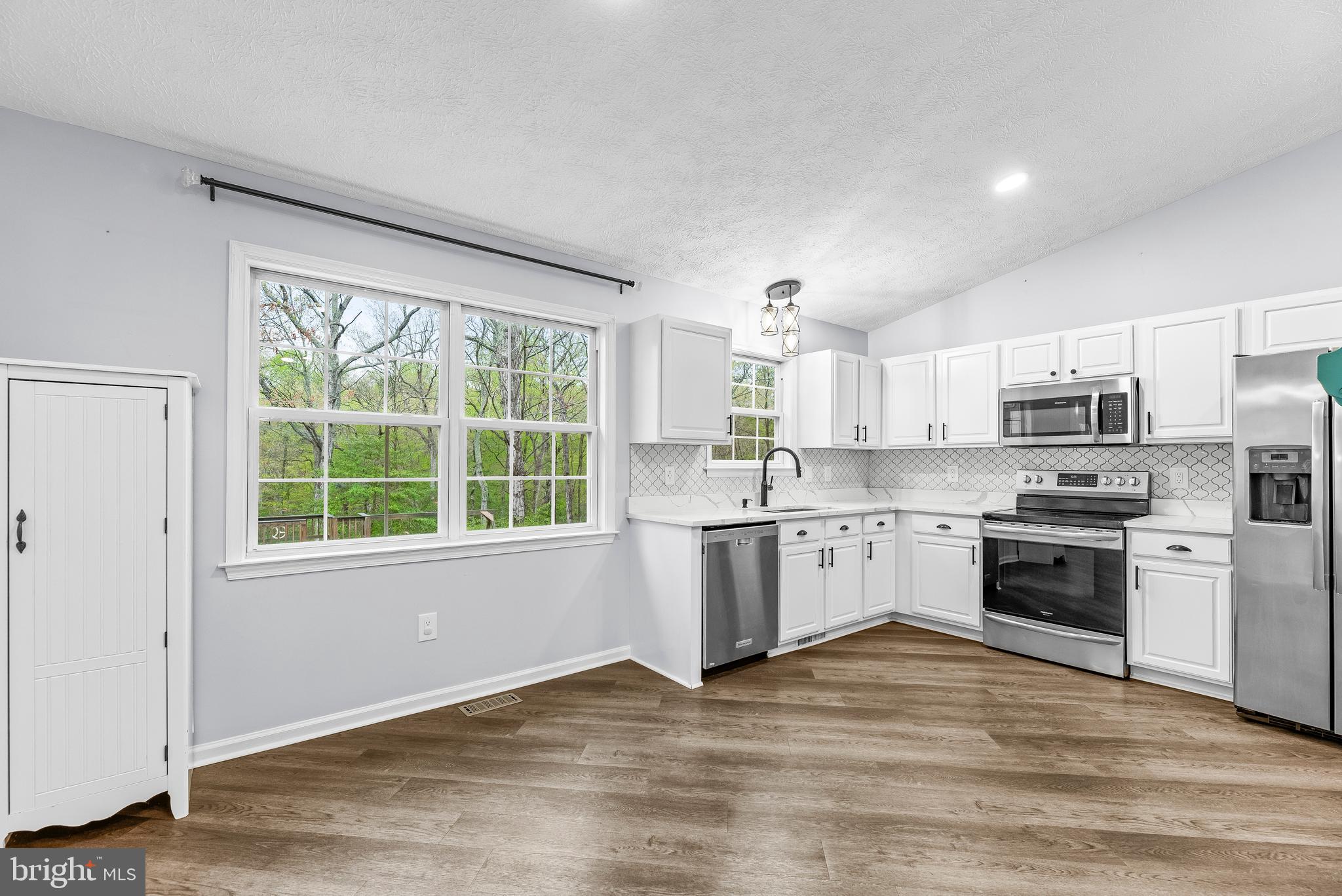 307 Red Cloud Road Lusby, MD 20657 - Photo 8 of 35 a kitchen with a stove a sink dishwasher a refrigerator and white cabinets with wooden floor