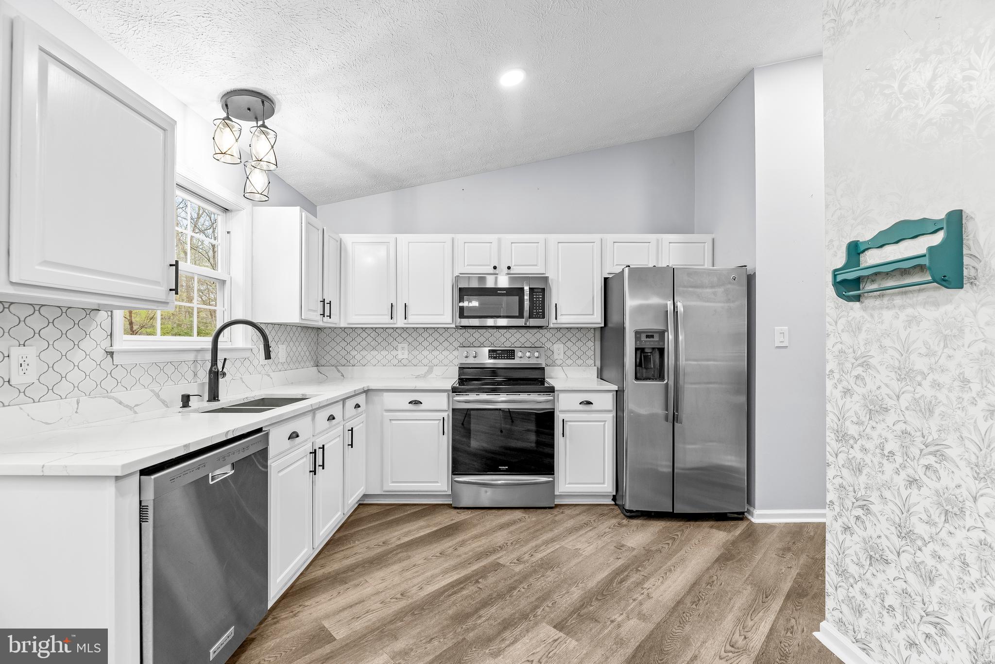 307 Red Cloud Road Lusby, MD 20657 - Photo 10 of 35 a kitchen with stainless steel appliances granite countertop a sink and a refrigerator