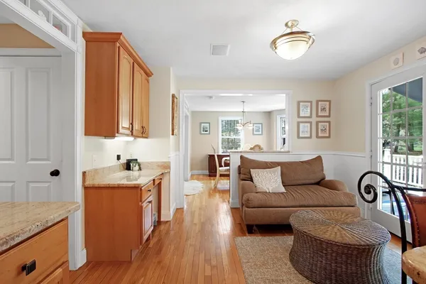 a living room with furniture kitchen view and a wooden floor