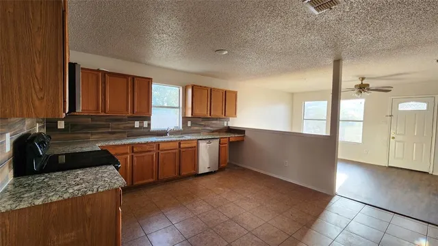 a large kitchen with granite countertop a sink and cabinets