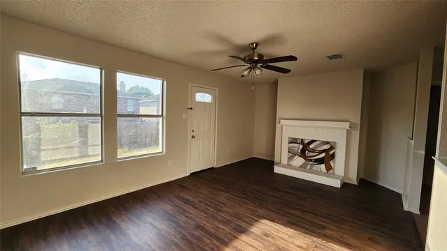 an empty room with wooden floor a ceiling fan and windows