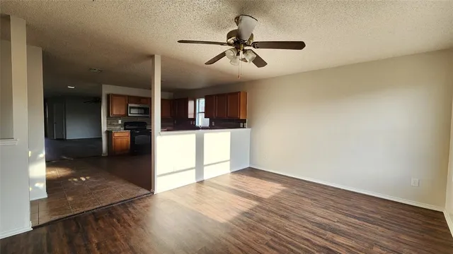 an empty room with wooden floor ceiling fan and windows