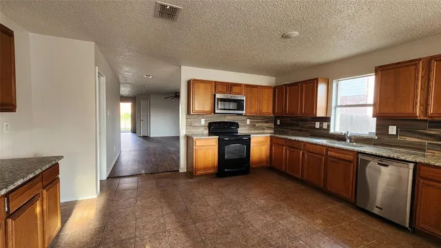 a kitchen with granite countertop a stove top oven a sink dishwasher a dining table and chairs with wooden floor