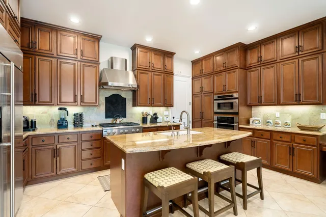 a kitchen with stainless steel appliances granite countertop a stove refrigerator sink and cabinets