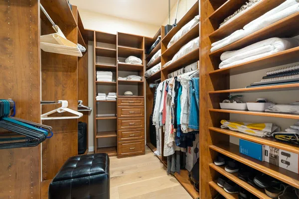 a view of walk in closet with clothes and shoes