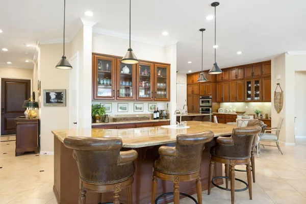 an open kitchen with granite countertop a stove a sink a oven a dining table and chairs
