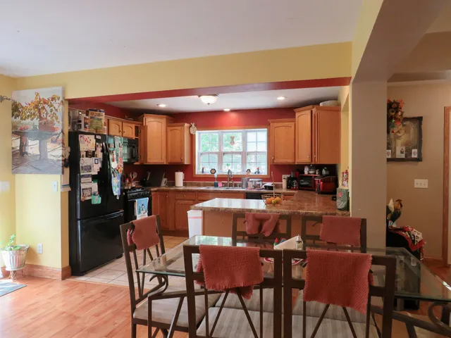 a dining hall with stainless steel appliances a dining table and chairs with wooden floor