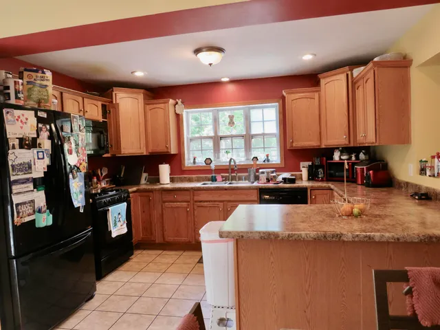 a kitchen with stainless steel appliances granite countertop a refrigerator a sink a stove top oven and a counter space