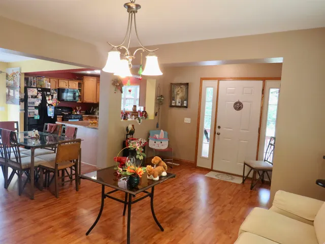 a dining room with wooden floor a chandelier a glass table and chairs