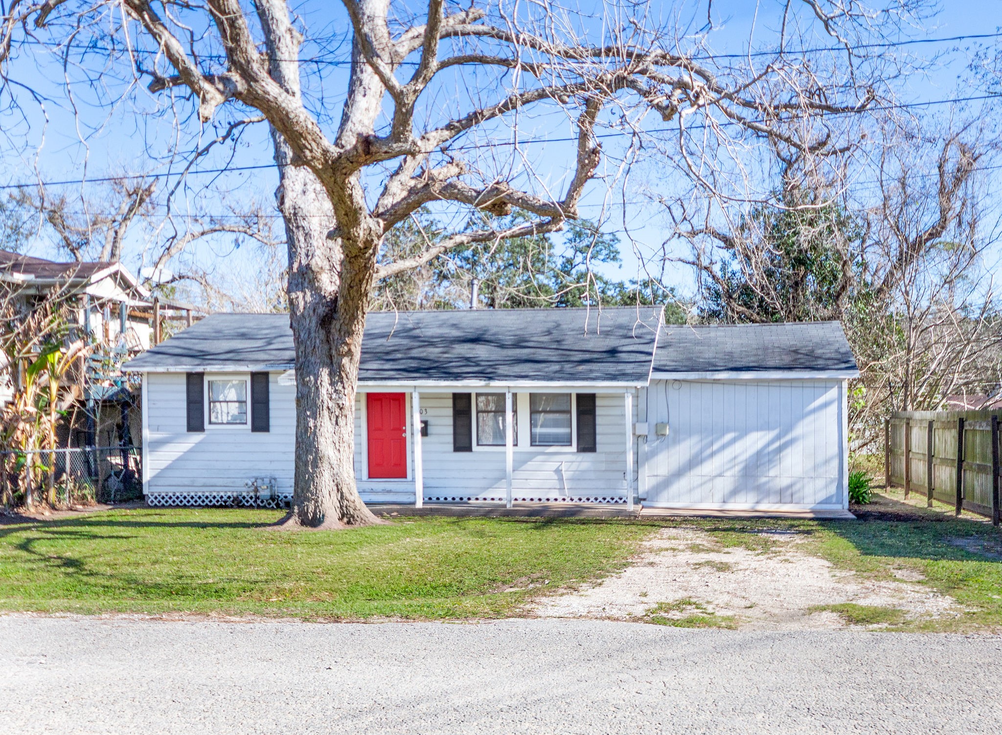 Welcome home! This cozy home offers a welcoming ambiance with its vibrant red door and serene surroundings.