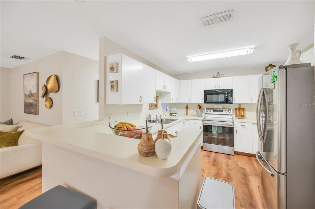 10318 Summerview Circle Riverview, FL 33578 - Photo 23 of 39 a white kitchen with stainless steel appliances a stove a sink a refrigerator white cabinets and wooden floor