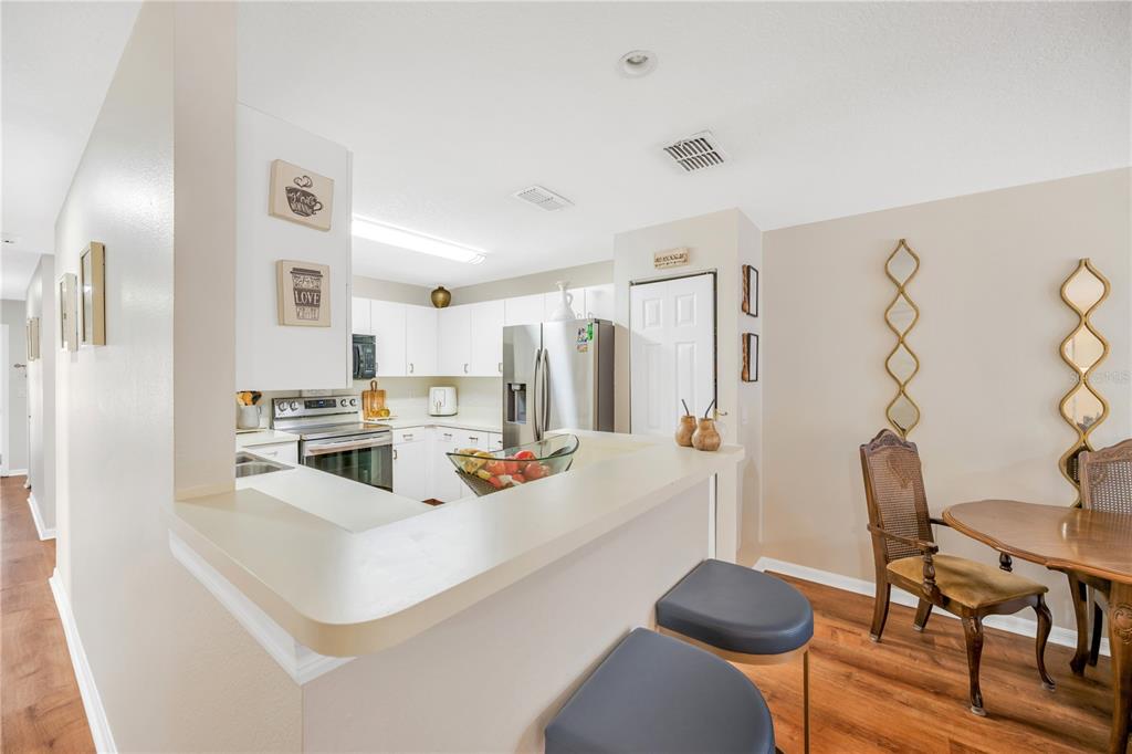 10318 Summerview Circle Riverview, FL 33578 - Photo 25 of 39 a white kitchen with stainless steel appliances a refrigerator a stove a dining table and chairs with wooden floor