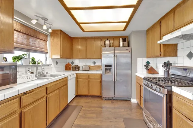 a kitchen with stainless steel appliances granite countertop a refrigerator a sink a stove and washer