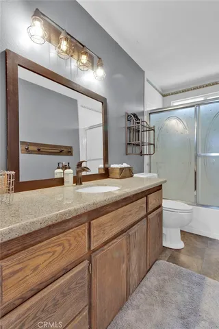 a bathroom with a granite countertop sink a toilet and a mirror