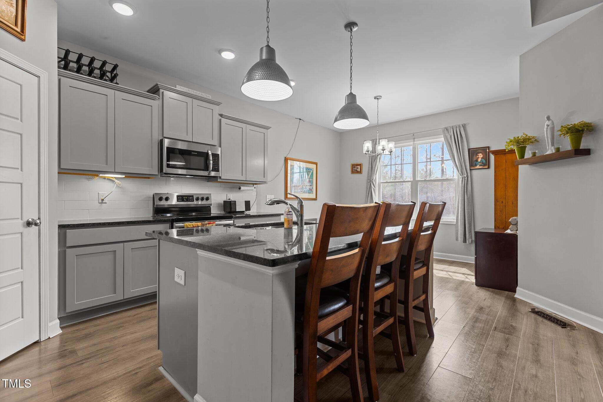 240 Northview Drive Middlesex, NC 27557 - Photo 19 of 58 a kitchen with stainless steel appliances granite countertop a stove a sink a microwave a refrigerator a dining table and chairs with wooden floor