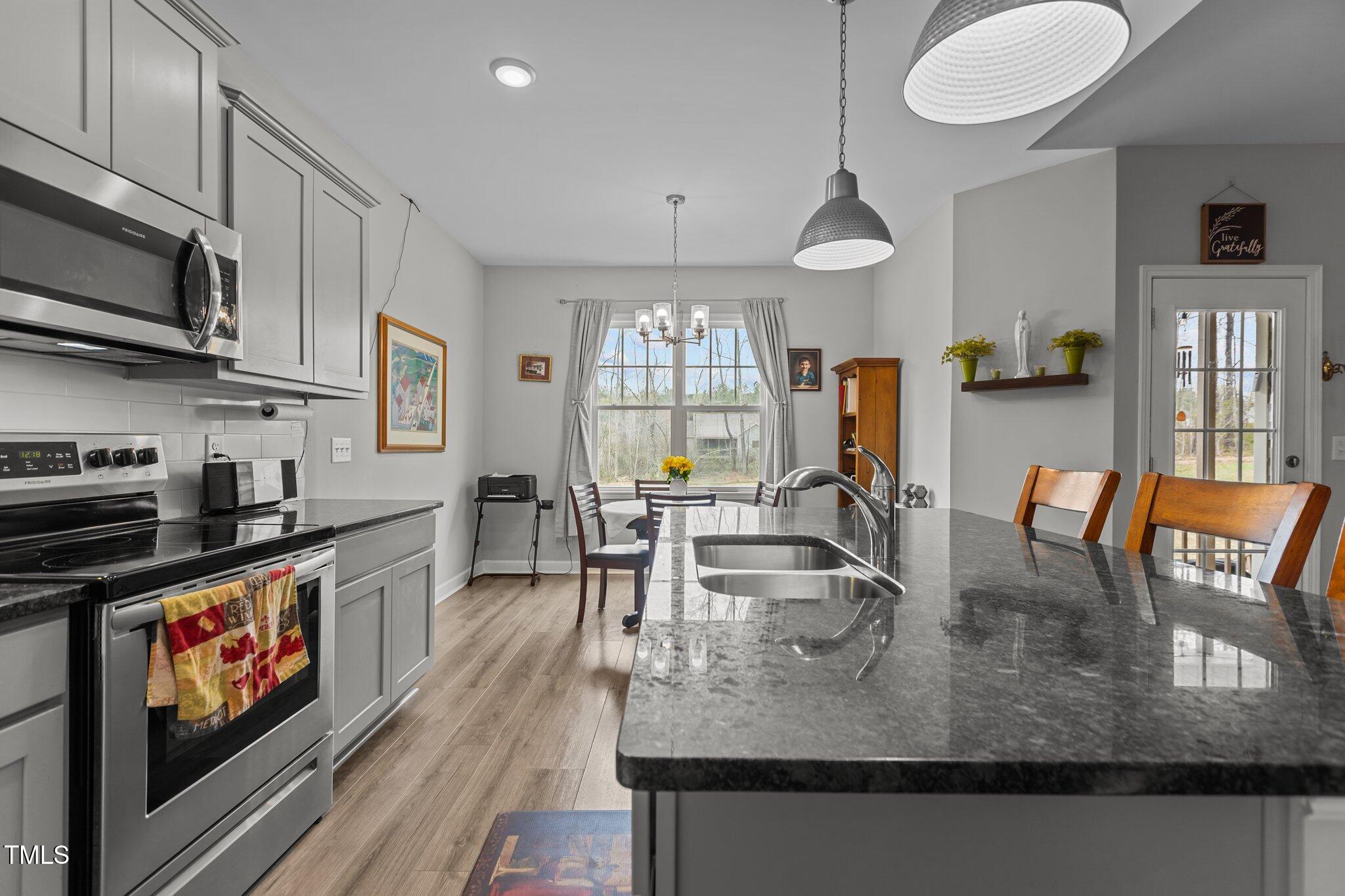 240 Northview Drive Middlesex, NC 27557 - Photo 21 of 58 a kitchen with stainless steel appliances granite countertop a stove top oven a sink a dining table and chairs with wooden floor