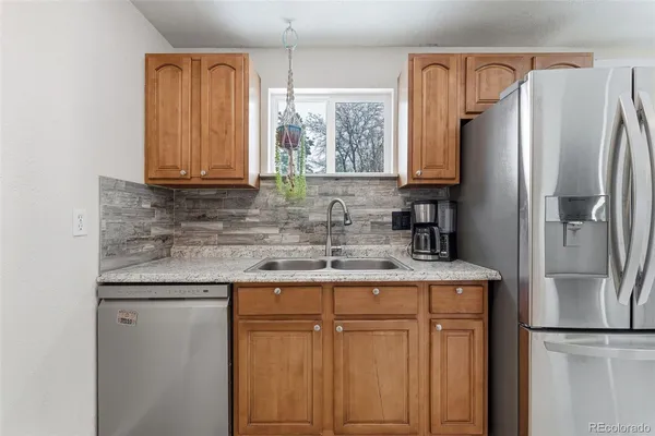 a kitchen with stainless steel appliances granite countertop a refrigerator a sink and white cabinets
