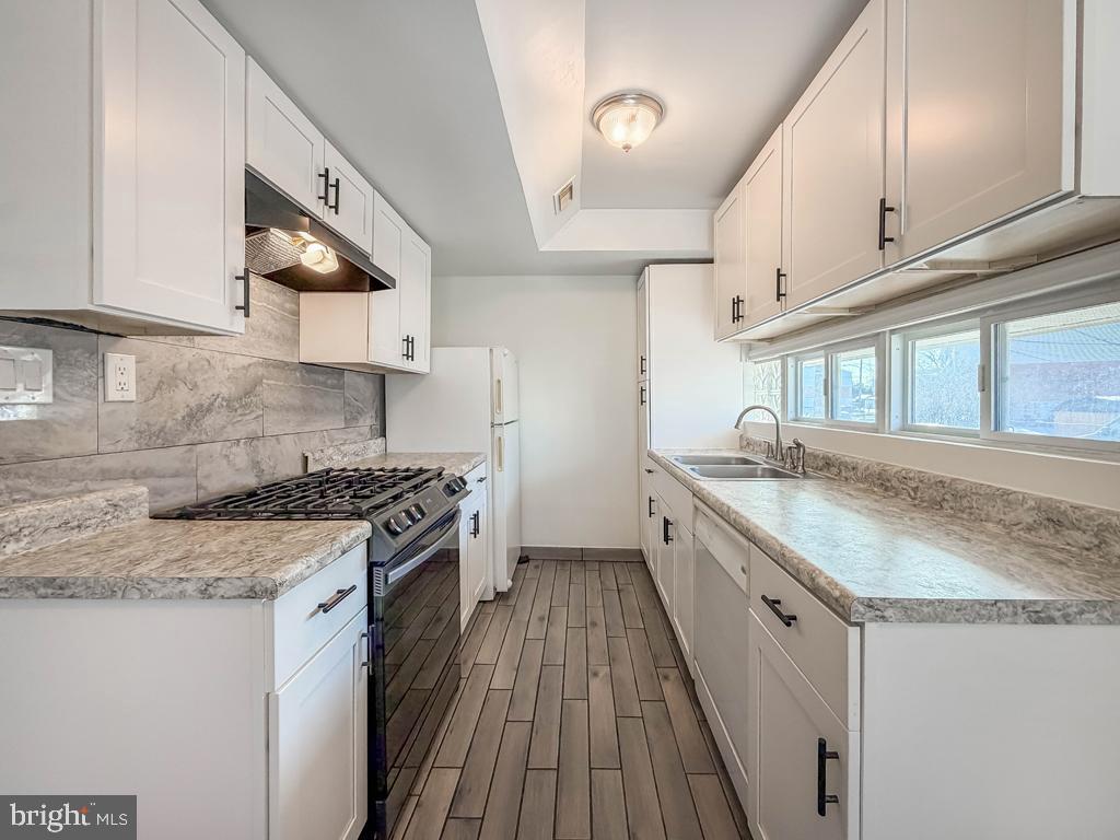 3850 Woodhaven Road, Unit 901 Philadelphia, PA 19154 - Photo 11 of 24 a kitchen with granite countertop a sink a stove top oven and cabinetry