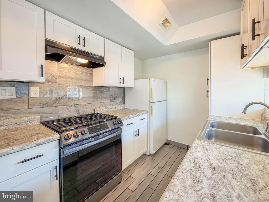 3850 Woodhaven Road, Unit 901 Philadelphia, PA 19154 - Photo 10 of 24 a kitchen with granite countertop a sink a stove a refrigerator and cabinets