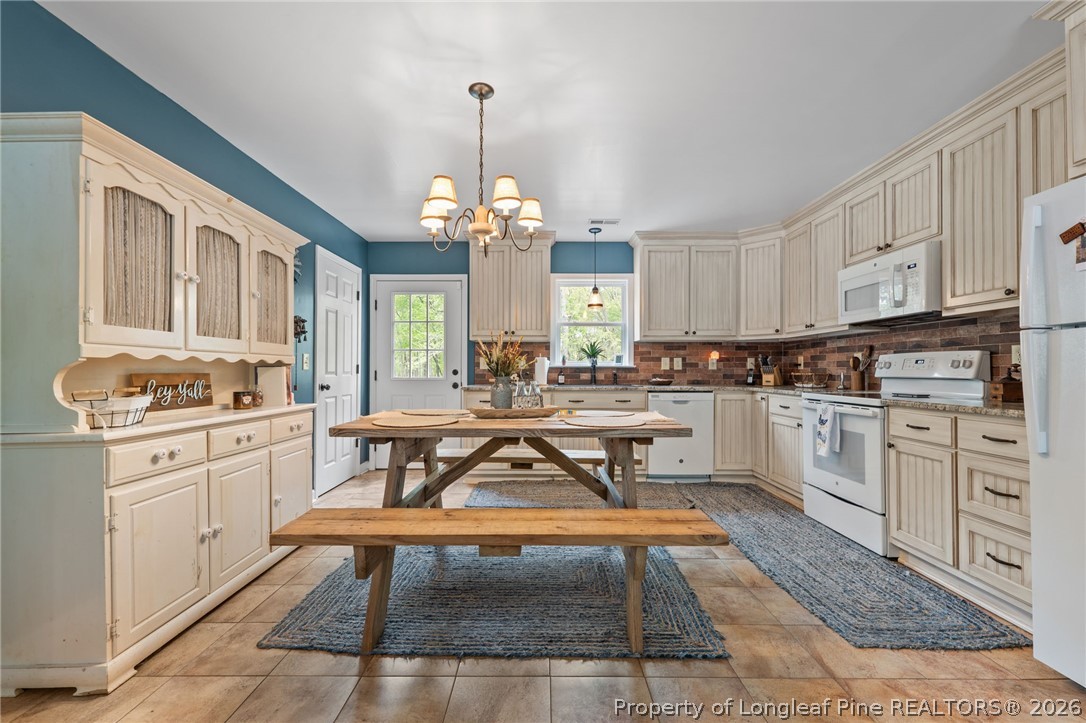 186 Lewis Brown Road Bennett, NC 27208 - Photo 11 of 48 a kitchen with stainless steel appliances granite countertop a stove top oven a sink dishwasher a dining table and chairs with white cabinets