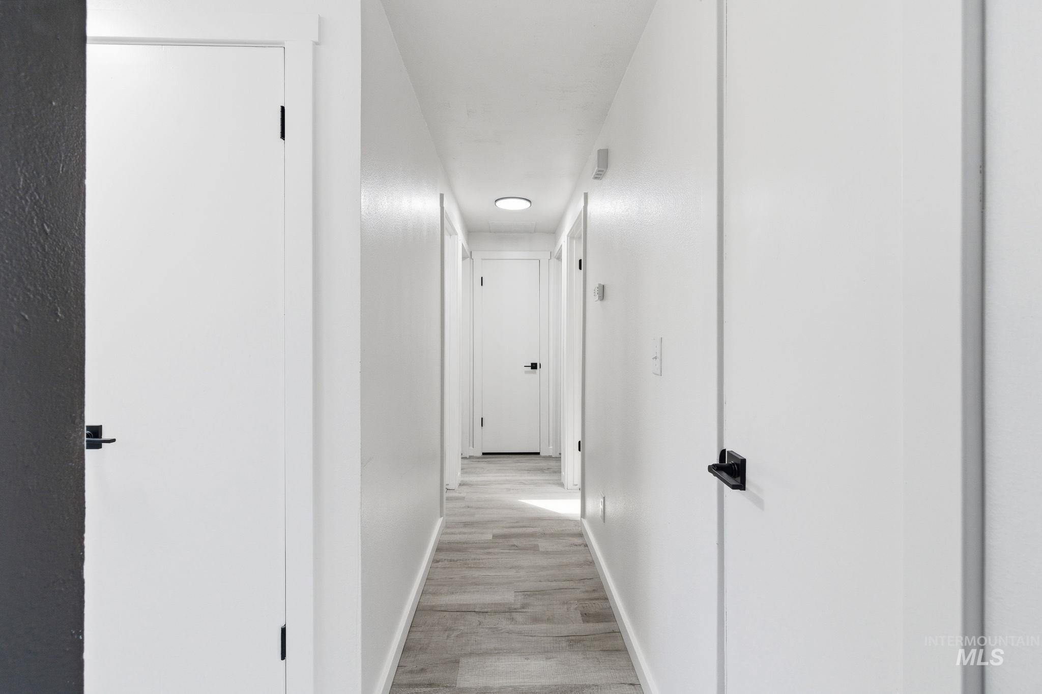 2224 Rachel Circle Boise, ID 83706 - Photo 8 of 50 Hallway featuring light wood-finish flooring, white walls, and contemporary black door hardware